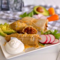 Christmas Homemade Tamales on a plate with toppings.