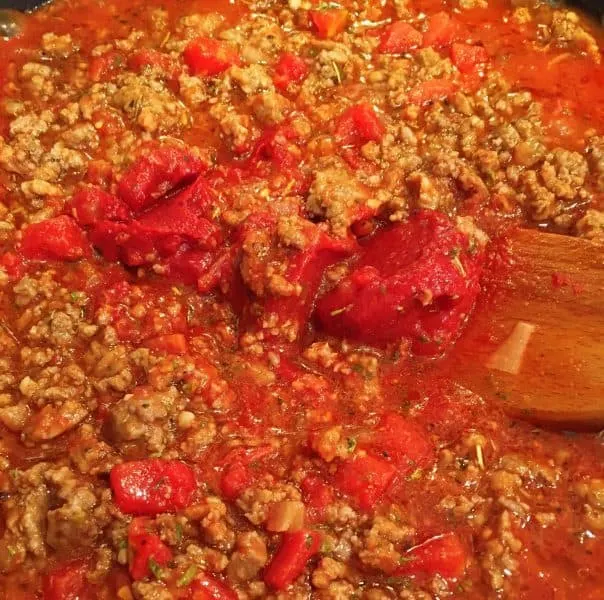 Adding tomato sauce and paste to cooked meat for spaghetti sauce