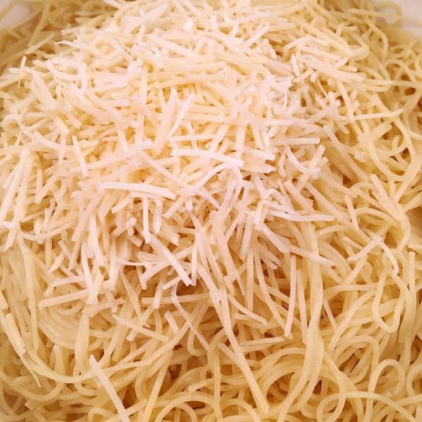 adding parmesan cheese to cooked spaghetti