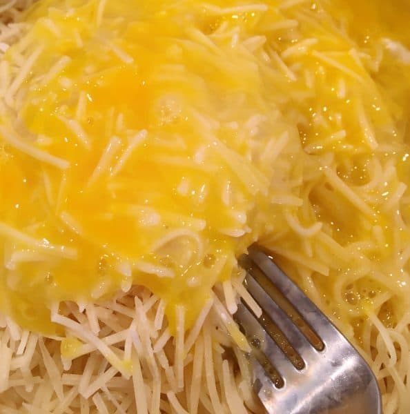 Adding eggs to spaghetti mixture for base of casserole