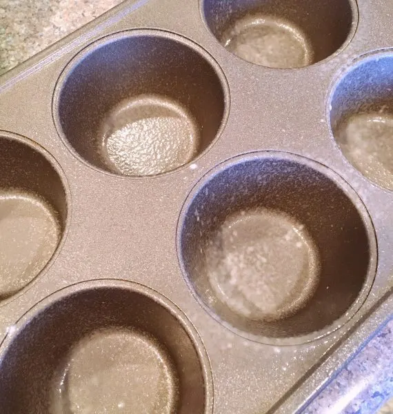 Muffins tin prepared with baking spray