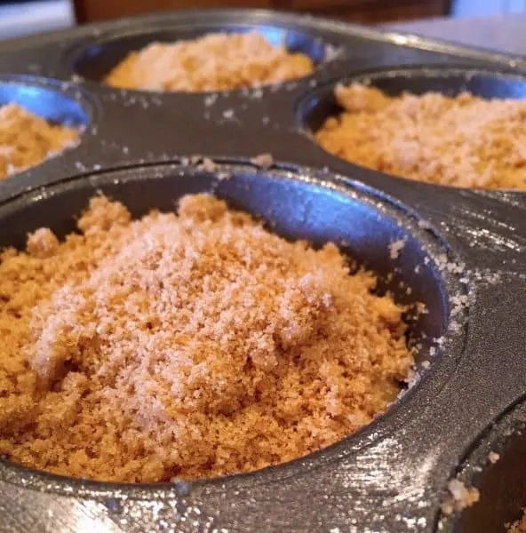 Crumb topping on top of banana muffin batter in muffin tin