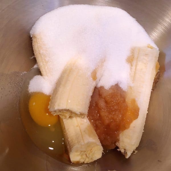 Bowl of Mixer with banana, eggs, sugar, and vanilla.