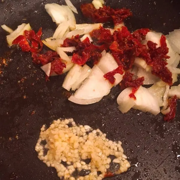 Garlic, onions, and dried tomatoes in a skillet