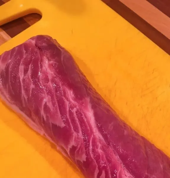Pork Tenderloin on a yellow cutting board ready for slicing