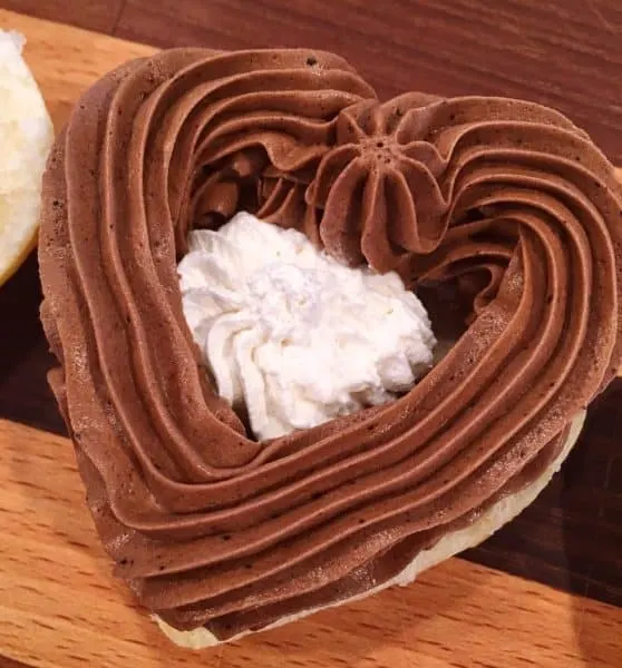 Puff pastry being filled with chocolate filling and whipped cream