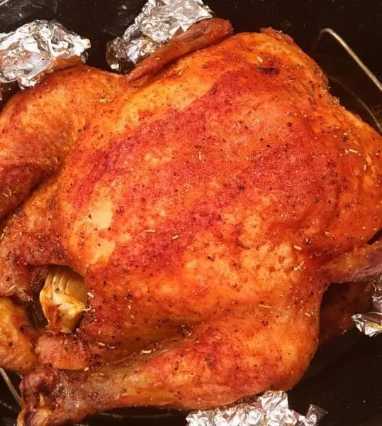 Whole slow roasted chicken in roasting pan coming out of the oven