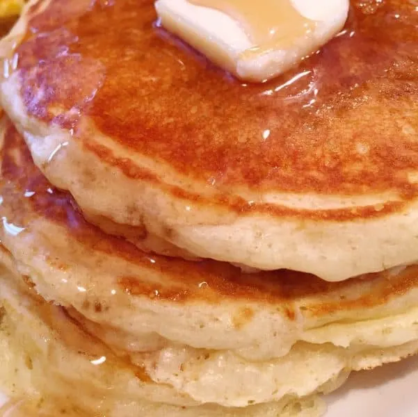 Stack of Fluffy Buttermilk Pancakes with a pat of butter and rich maple syrup
