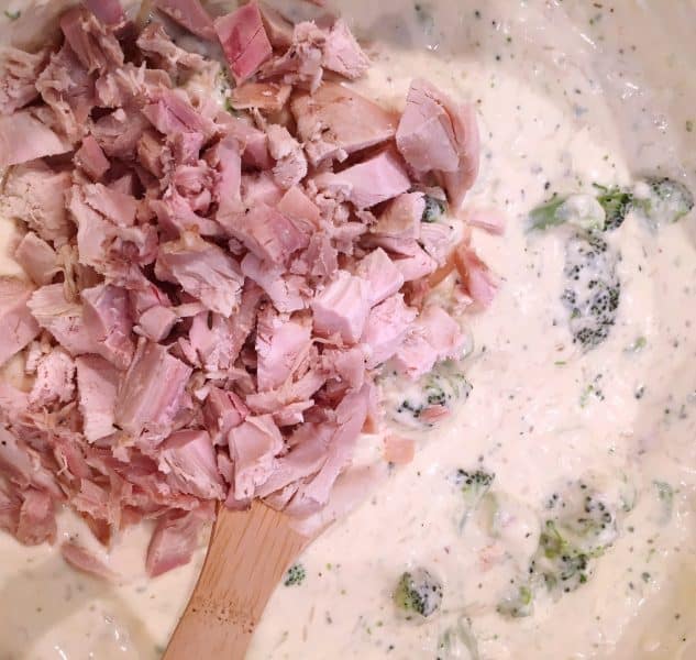 Soup and Broccoli Mixture in a bowl with Chicken being added