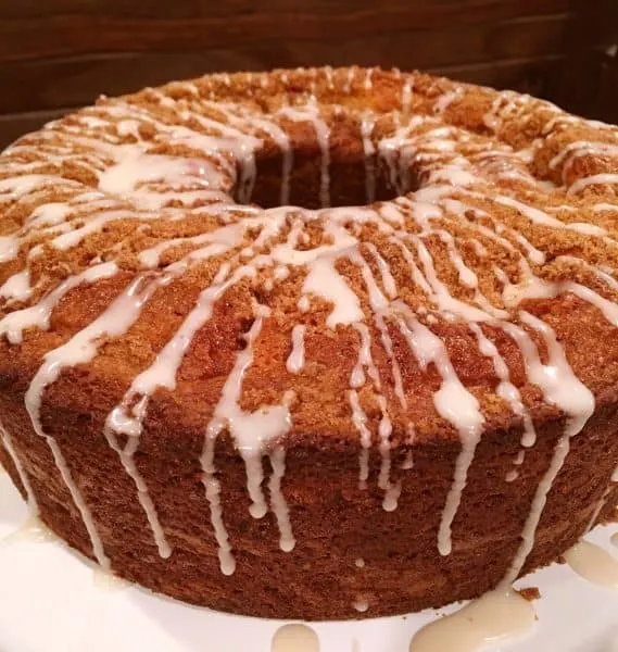 Full Cake Mix Cinnamon Bundt Cake on cake stand with vanilla glaze icing drizzle.
