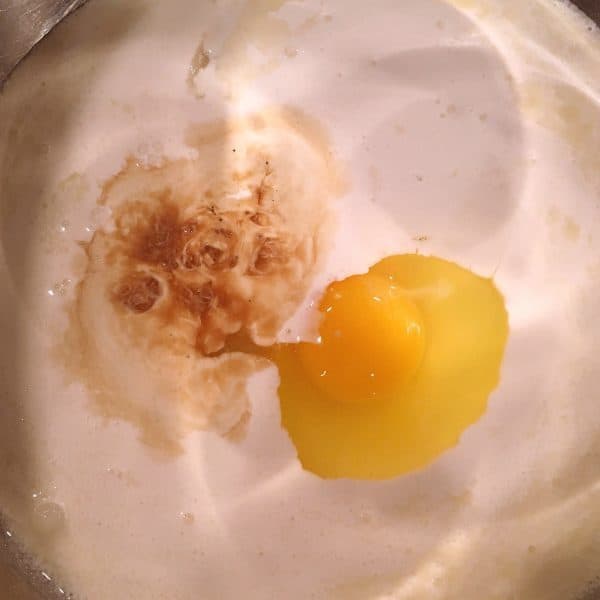 Lage bowl filled with cream, sugar, vanilla, and egg to create batter for bread pudding