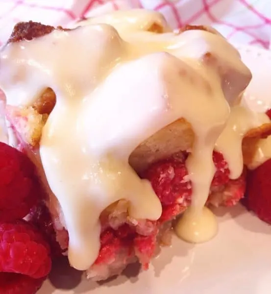 A square of Raspberry Bread Pudding Drizzled with Warm Vanilla Cream Sauce.