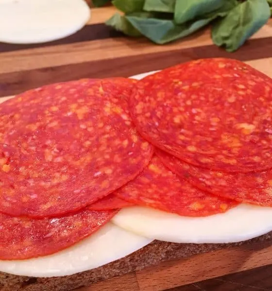 Slice of break with pesto, layer of Provolone Cheese, and Pepperoni