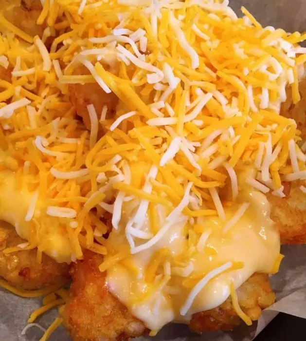 Parchment lined skillet with layer of fried tater tots and cheese