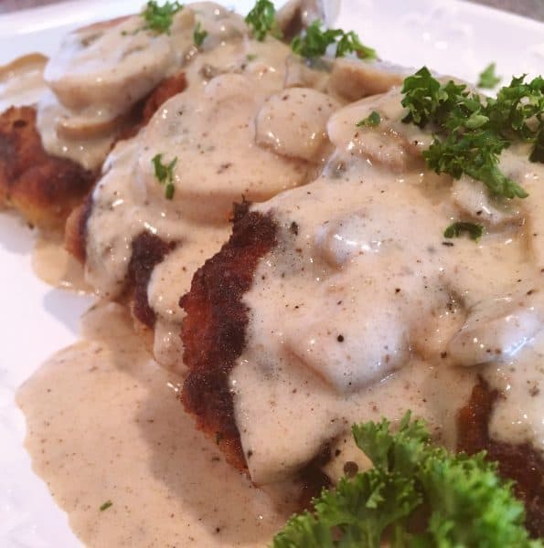 Fried Pork Chops on a serving platter with Creamy Mushroom Gravy