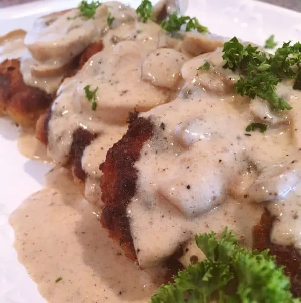Fried Pork Chops on a serving platter with Creamy Mushroom Gravy
