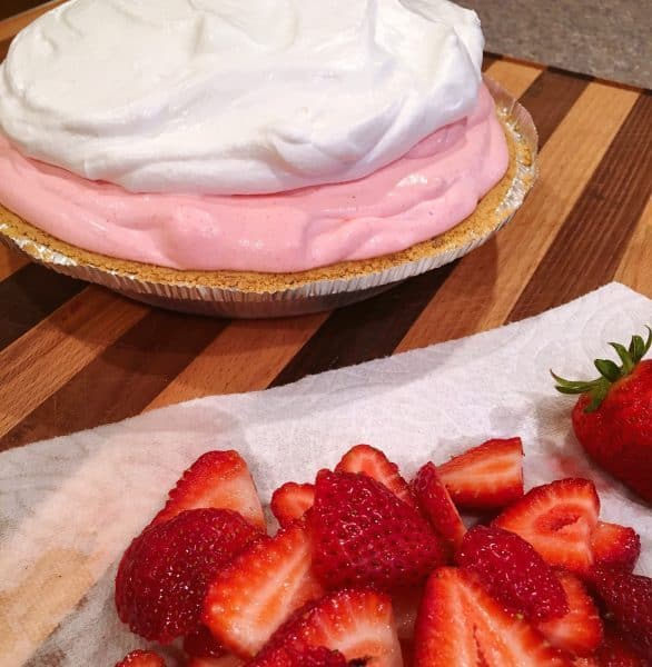 Adding Cool Whip topping on top of pie with fresh sliced berries