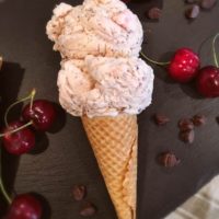 Two scoops of Cherry Chocolate Chip Ice cream on a cone