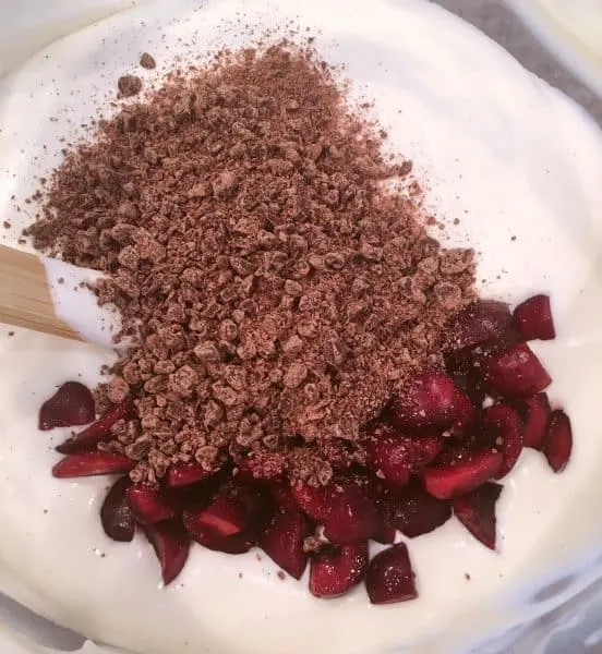 Adding in chocolate and cherries to ice cream mixture