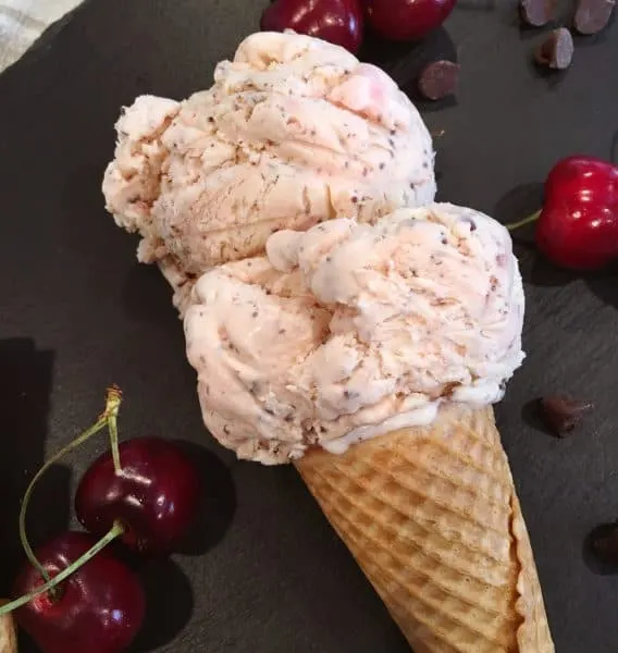 Two scoops of Cherry Chocolate Chip Ice cream on a cone.