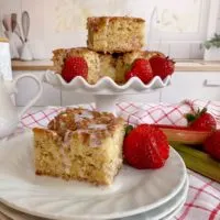 Rhubarb Sour Cream Coffee cake on a serving plate and piled high on a cake plate.