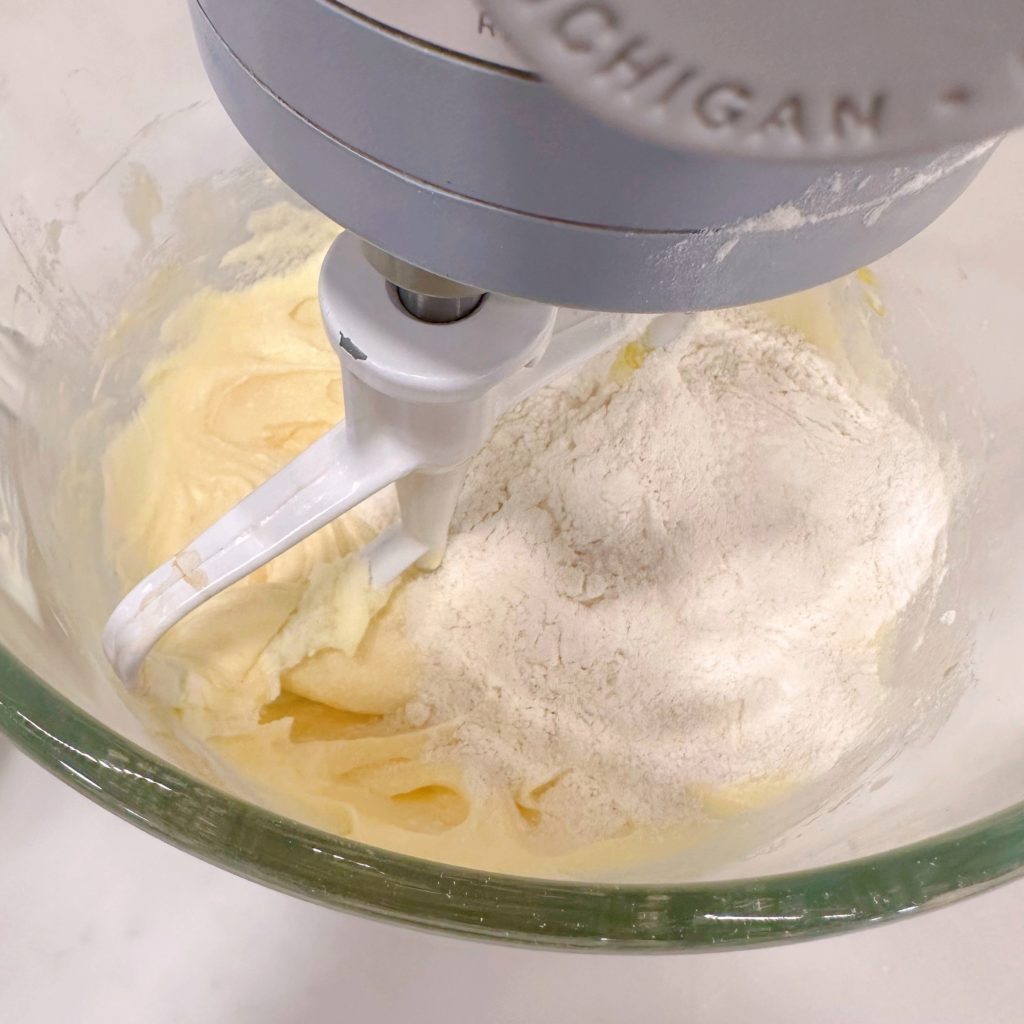Adding dry ingredients to wet ingredients in a mixing bowl.