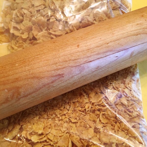 Corn Flakes in a bag with rolling pin creating crumbs
