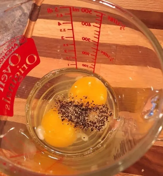 Eggs and seasonings in measuring cup.