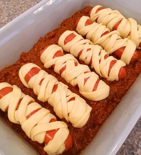 wrapped mummy dogs in a chili lined baking dish