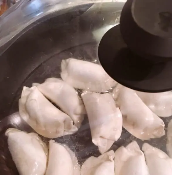 Potstickers boiling in a covered skillet