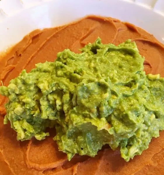 Spread layer of guacamole over bean dip