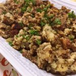 Best Sausage and Herb Stuffing in a white serving bowl garnished with fresh parsley.