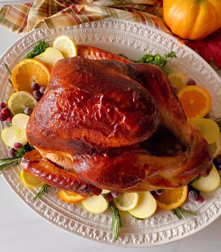 Roasted Turkey on a platter surrounded by sliced fruit.