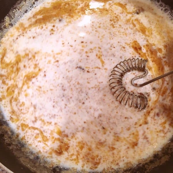 Mixing milk into roux to create gravy