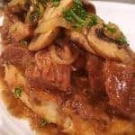 Hot Roast Beef in gravy on a thick slice of bread with mushrooms and a sprinkle of parsley.