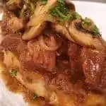 Hot Roast Beef in gravy on a thick slice of bread with mushrooms and a sprinkle of parsley.