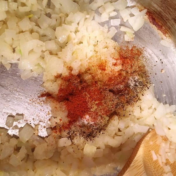 Spices being added to onions and garlic