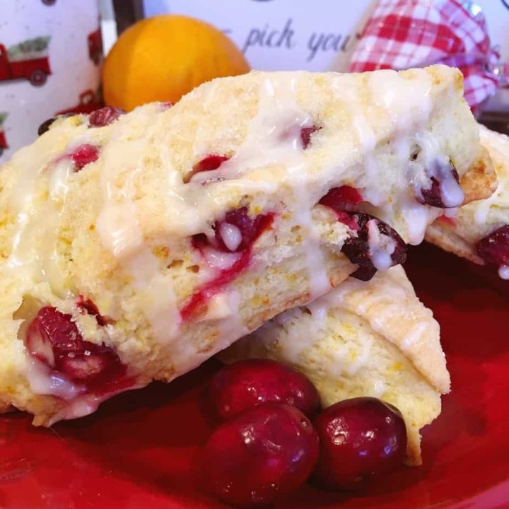 Cranberry Orange Scones stack with fresh cranberries around them.