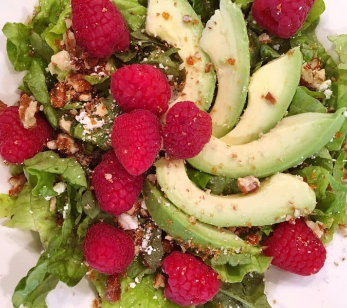 Adding Avocado and Raspberries to salad.