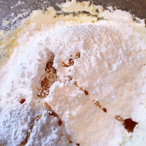mixing in sugar and vanilla into frosting