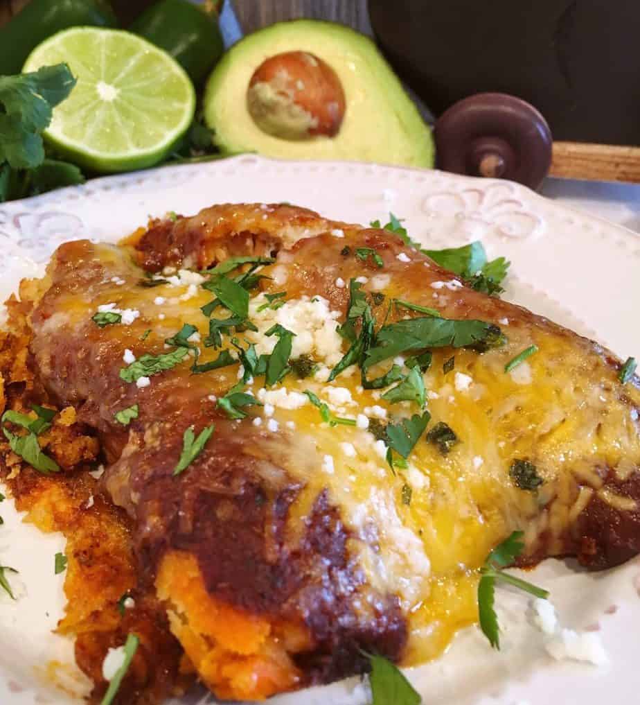 Tamale Casserole serving on a white plate with enchilada sauce.