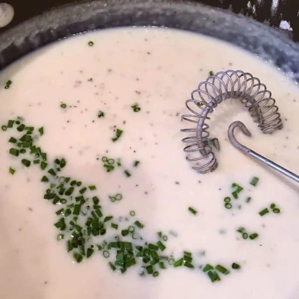 Cream sauce in pan adding chives