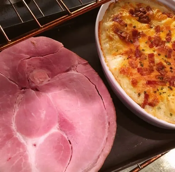 Ham steak on cookie sheet with potatoes