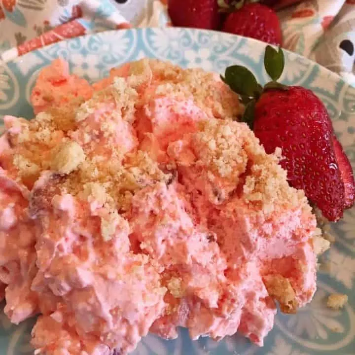 Strawberry Pineapple Fluff Salad serving on a plate with a strawberry garnish.