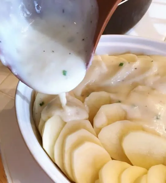 sliced potatoes in baking dish with cream sauce