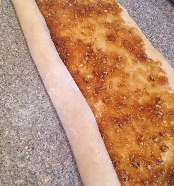 Carrot Cake mix cinnamon roll dough being rolled into long roll.