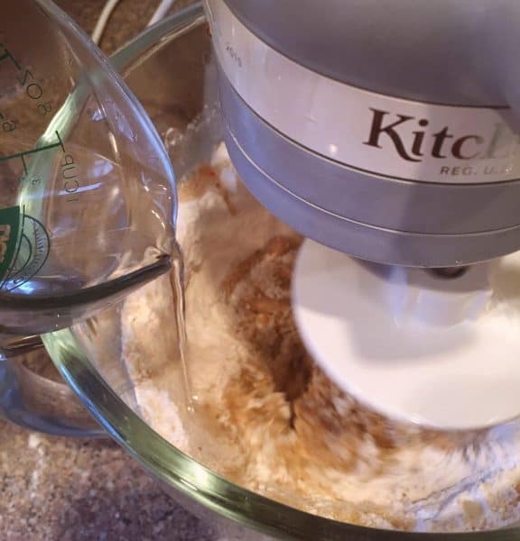 Adding hot water to mixing bowl while carrot cake mix is mixing