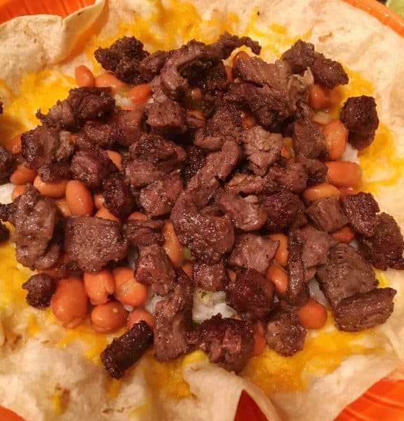 Layer of diced seasoned skirt steak on pinto beans