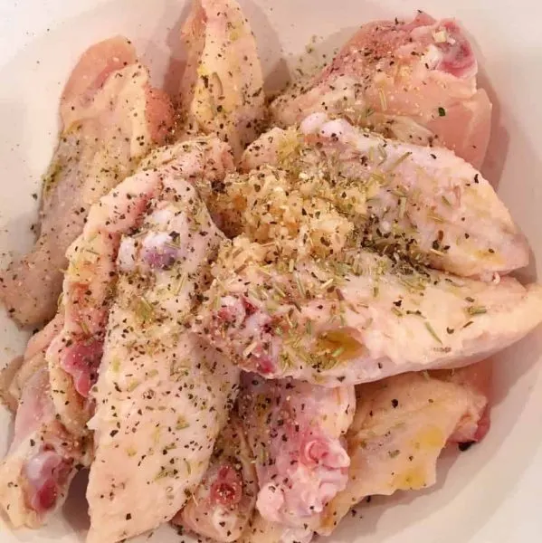 Garlic Parmesan Wings in bowl with olive oil and seasonings.