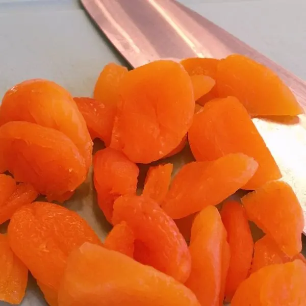 Dried apricots on cutting board with sharp knife